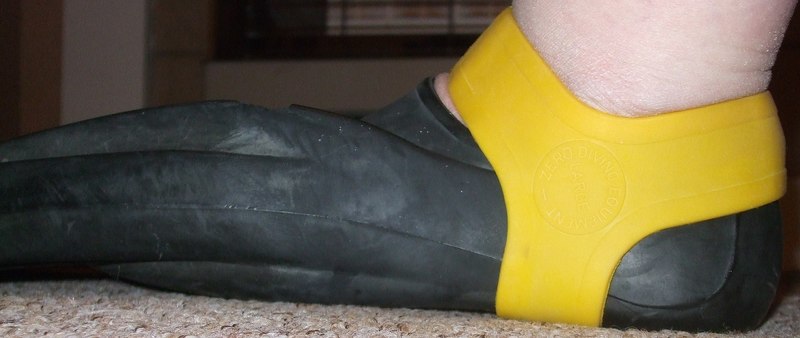 1920px-Yellow_fin_grip_retaining_a_Technisub_Ala_swimming_fin_on_the_foot.jpg