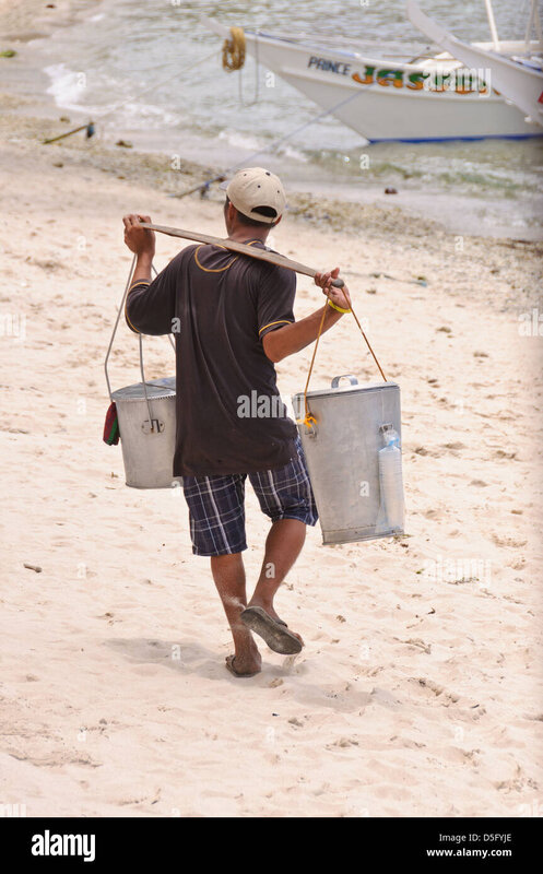 asian-man-beach-vendor-carries-two-heavy-buckets-over-the-shoulder-D5FYJE.jpg